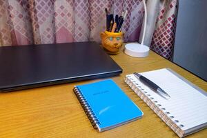 Office table with blank notebook, pen and laptop. office desk top view with blank notebook photo