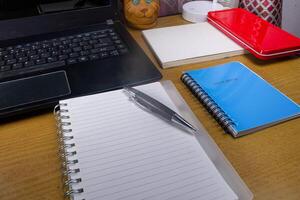 Office table with blank notebook, pen and laptop. office desk top view with blank notebook photo