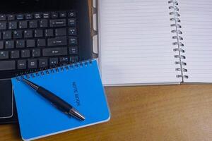 Office table with blank notebook, pen and laptop. office desk top view with blank notebook photo
