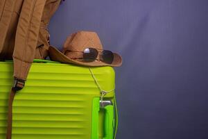 Tourist stuff. Straw hat, shoes, and green suitcase on grey background. Travel item. photo