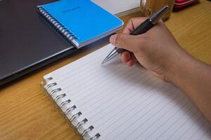 Hands holding pencils and notebooks. Hand with a pen is writing in a notebook. Mock-up Concept. photo