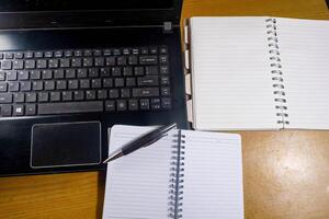 Office table with blank notebook, pen and laptop. office desk top view with blank notebook photo