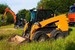 Two small excavators next to a truck. A new generation of special equipment at an open location on a sunny day photo