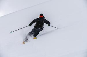 Skier man in action. Front view. Fast descent at high speed. Skier on skis in high mountains. Descent. Skiing in the mountains. Snow dust photo