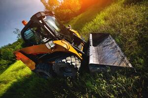 Excavator against the background of a green field and trees. Wide angle shooting photo