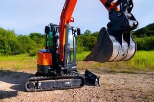 bulldozer stands on a piece of land against the backdrop of a bright blue sky and green trees. construction equipment ready to work photo