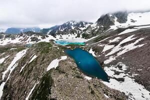 Aerial view of three frozen mountain lakes, shot with a drone at a wide angle. Icy cloudy day in the snowy mountains, in the wilderness photo