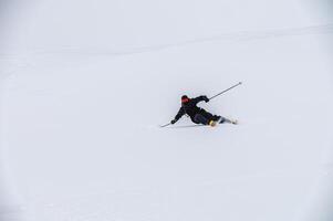 Skier man in action. Front view. Fast descent at high speed. Skier on skis in high mountains. Descent. Skiing in the mountains. Snow dust photo