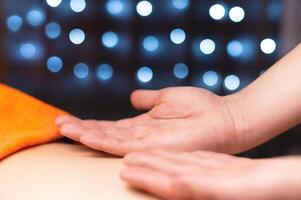 Masseur massaging back close-up. Candlelight setting, spa salon, relaxing day off photo