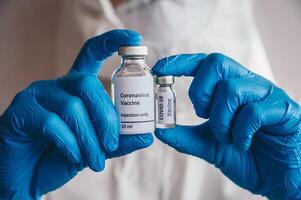 Close up of scientist doctor hand holding a sample test bottles of Covid-19 vaccine. photo