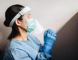Healthcare worker praying for god blessing while wearing safety equipment for working in hospital during coivd-19 pandemic. photo
