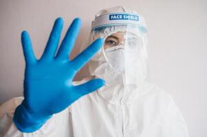 Healthcare worker wearing PPE suit for protect virus and show stop hand gesture for social distancing. Social distancing is the physical space between people to avoid spreading illness. photo