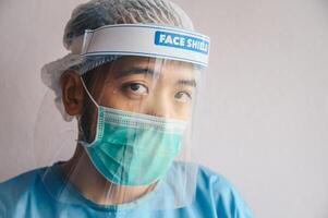 Portrait of Doctor having tired from work while wearing PPE suit for protect coronavirus disease. The wellbeing and emotional resilience are key components of maintaining essential care services. photo