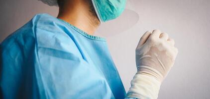 Close up of Doctor praying for God's blessings while wearing PPE suit for work at hospital in covid-19 pandemic outbreak. Conceptual of healthcare worker praying and hope everything will be better. photo