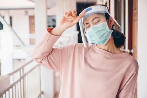 Asian woman wearing mask and face shield before going outside her room for prevent and protection covid-19 virus disease. photo