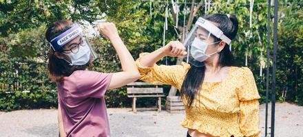 Two woman bump elbows for greeting during coronavirus epidemic. The elbow bump was suggested as an alternative way for reduce your risk of spreading or contracting the virus. photo