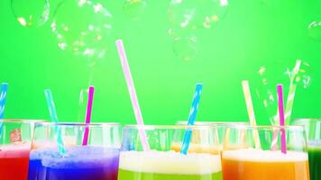 Colorful drinks are shown in glasses on a green background video