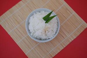 Cooked rice in a bowl with red background, top view. photo