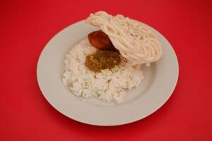 Rice with fried chicken and sambal in a white plate on a red background photo