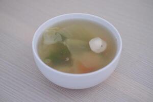 A bowl of soup on a wooden table photo