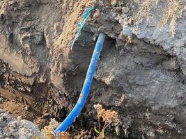A blue corrugated pipe partially exposed in a dirt trench at a construction site photo