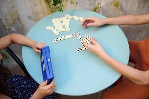 Children playing dominoes at a round blue table, focused on the game, enjoying quality time and developing strategy skills in a relaxed environment photo