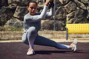Woman performing a squat with a TRX in outdoor gym setting, showcasing strength and balance in fitness training photo