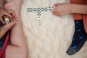 Children playing a game of dominoes on a soft furry surface, enjoying leisure time and learning through play while bonding and developing cognitive skills. photo