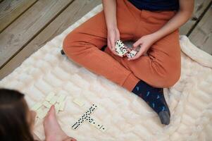 Close-up of two people playing a game of dominos on a cozy blanket, highlighting leisure, concentration, and strategy in a relaxed home setting. photo