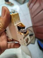 A hand holds a burnt Miniature Circuit Breaker MCB with visible signs of damage. The background shows a tiled floor and part of a door, emphasizing the context of a repair situation photo