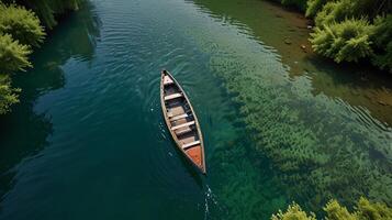 top down view of an empty boat in a crystal-clear river lined with green bushes photo