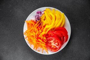 salad fresh vegetables cut into a plate tomato, carrot, pepper, onion juicy fresh gourmet food background on the table rustic food top view copy space keto and paleo diet Vegetarian and vegan photo