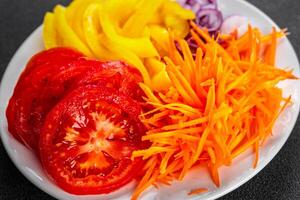 salad fresh vegetables cut into a plate tomato, carrot, pepper, onion juicy fresh gourmet food background on the table rustic food top view copy space keto and paleo diet Vegetarian and vegan photo