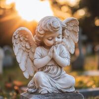 Peaceful angel statue with folded hands in prayer illuminated by warm sunlight photo