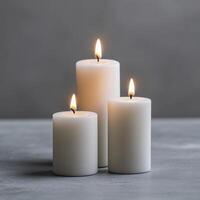 Pillar candles burning against a smooth gray background in a minimalist setting photo