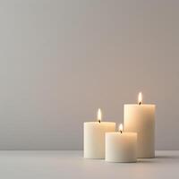 White candles burning softly against a neutral background in a minimalist composition photo