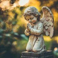 Kneeling angel statue in prayer with a soft golden light in a tranquil garden photo