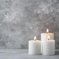 Candles burning on a gray textured background in a minimalist arrangement photo