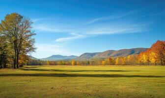 Autumn landscape with open field, colorful trees, distant mountains photo