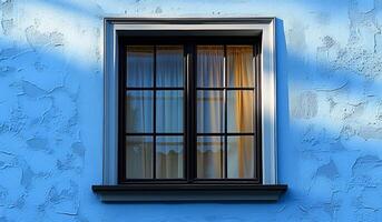 A window with a curtain is shown in a blue building. The sunlight is shining through the window, creating a warm and inviting atmosphere photo