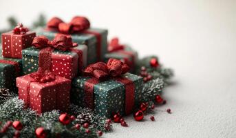 A stack of presents with red bows on top and green boxes underneath. The presents are surrounded by pine needles and red and green decorations photo