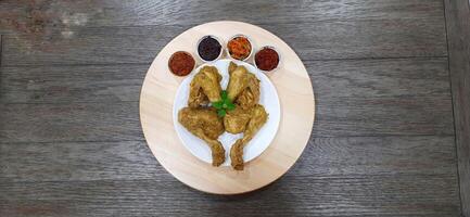 Ayam ungkep bumbu kuning or boiled chicken with curry seasoning and coconut water. Served with varian sambal or hot chili sauce. Ready to fried photo