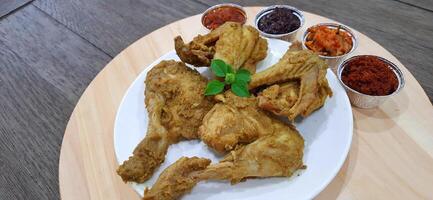 Ayam ungkep bumbu kuning or boiled chicken with curry seasoning and coconut water. Served with varian sambal or hot chili sauce. Ready to fried photo