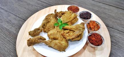 Ayam ungkep bumbu kuning or boiled chicken with curry seasoning and coconut water. Served with varian sambal or hot chili sauce. Ready to fried photo