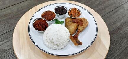 Ayam ungkep bumbu kuning or boiled chicken with curry seasoning and coconut water. Served with varian sambal or hot chili sauce. Ready to fried photo