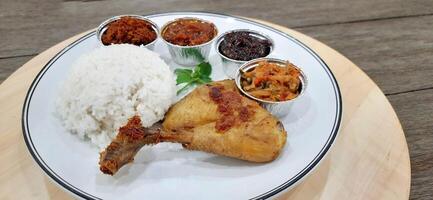 Ayam ungkep bumbu kuning or boiled chicken with curry seasoning and coconut water. Served with varian sambal or hot chili sauce. Ready to fried photo