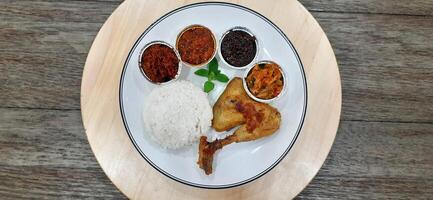 Ayam ungkep bumbu kuning or boiled chicken with curry seasoning and coconut water. Served with varian sambal or hot chili sauce. Ready to fried photo