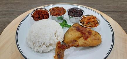 Ayam ungkep bumbu kuning or boiled chicken with curry seasoning and coconut water. Served with varian sambal or hot chili sauce. Ready to fried photo