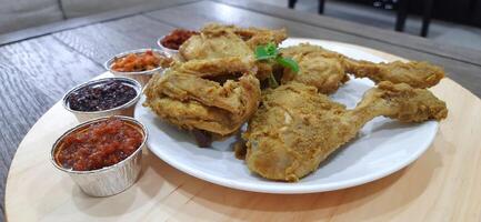 Ayam ungkep bumbu kuning or boiled chicken with curry seasoning and coconut water. Served with varian sambal or hot chili sauce. Ready to fried photo