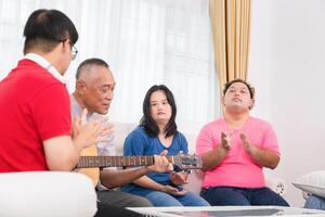 Senior man and grandchild having fun together while singing and playing the guitar in living room at home photo